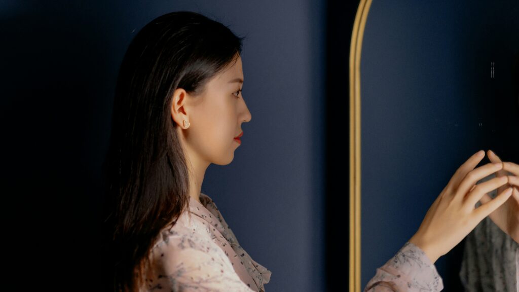 鏡を見つめる女性が、自分を受け入れようとしている様子